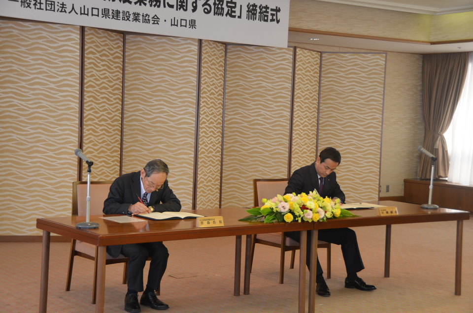 協定書に署名する村岡知事の写真