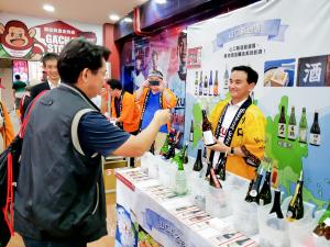 桃園球場ＰＲブースにおける日本酒をPRする村岡知事の写真
