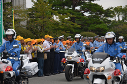 村岡知事に拍手で見送られる車両隊の写真