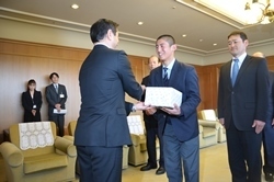 巻幡主将に記念品を贈呈し、握手を交わす村岡知事の写真