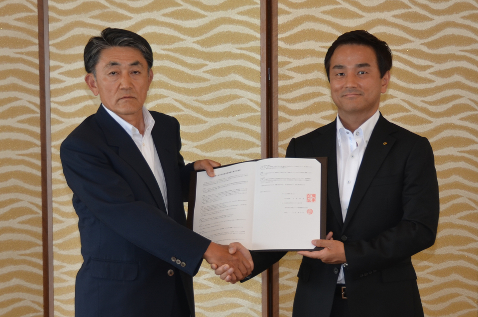 協定を掲げ、握手する与田支部長と村岡知事の写真