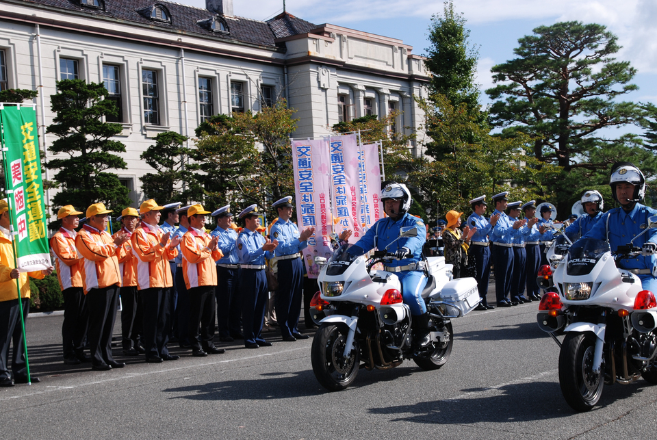 交通安全運動に繰り出す車両隊を見送る村岡知事の写真