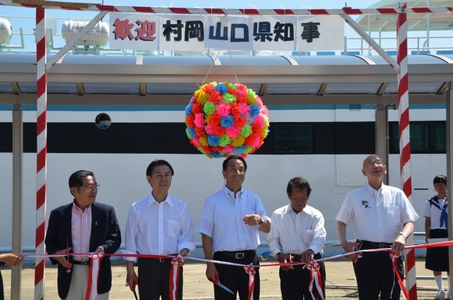 島民の歓迎の中、テープカットする村岡知事の写真