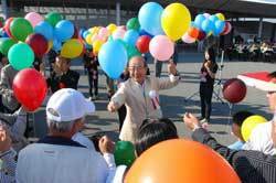 オープニングイベントで大空に舞い上げる風船を配る二井知事