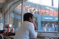 (1)バックネット裏から試合を観戦する宮本さんの画像