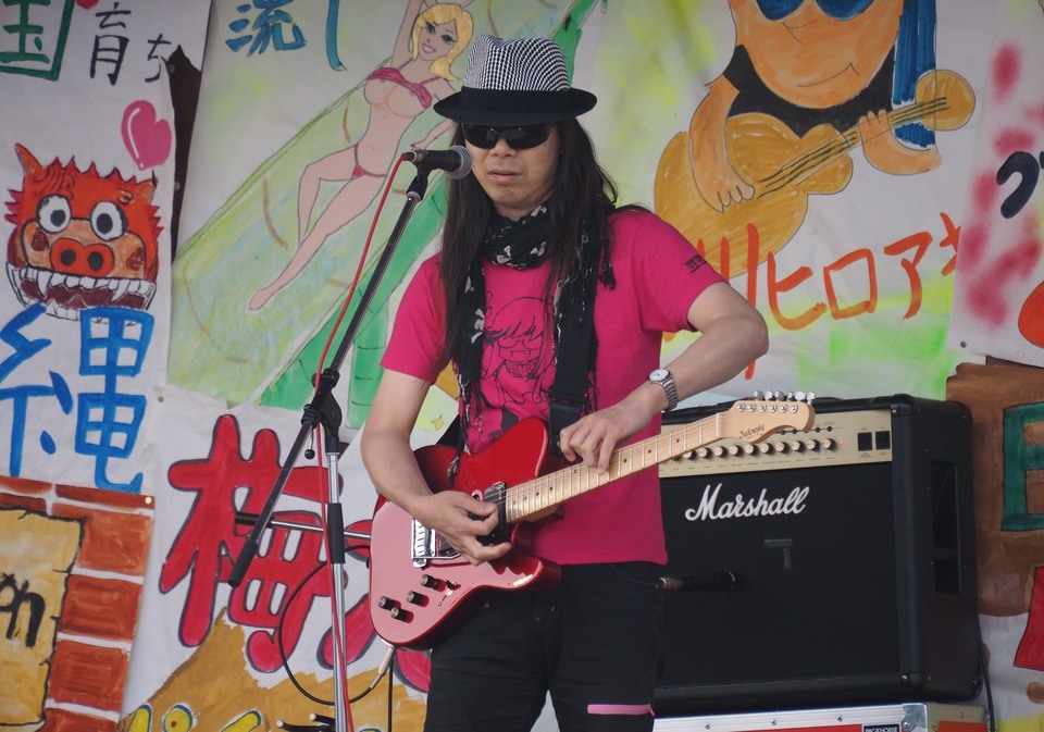 ギターのネックを逆さに持つ独特のスタイルで演奏する田川さん